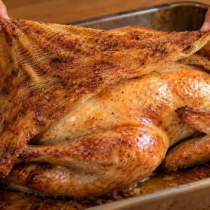 Browned butter-toasted cheesecloth being peeled off a roast turkey revealing golden skin underneath